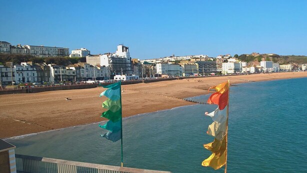 A beachside view with a wooden deck, a clear blue sky, and a cityscape in the background. - Location Location! Spacious 2 Bed Apt Hastings - Country & Sea Views (Hastings)