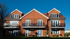 A two-story building with a brick facade, large windows, and balconies with outdoor furniture. - Location Location! Spacious 2 Bed Apt Hastings - Country & Sea Views (Hastings)