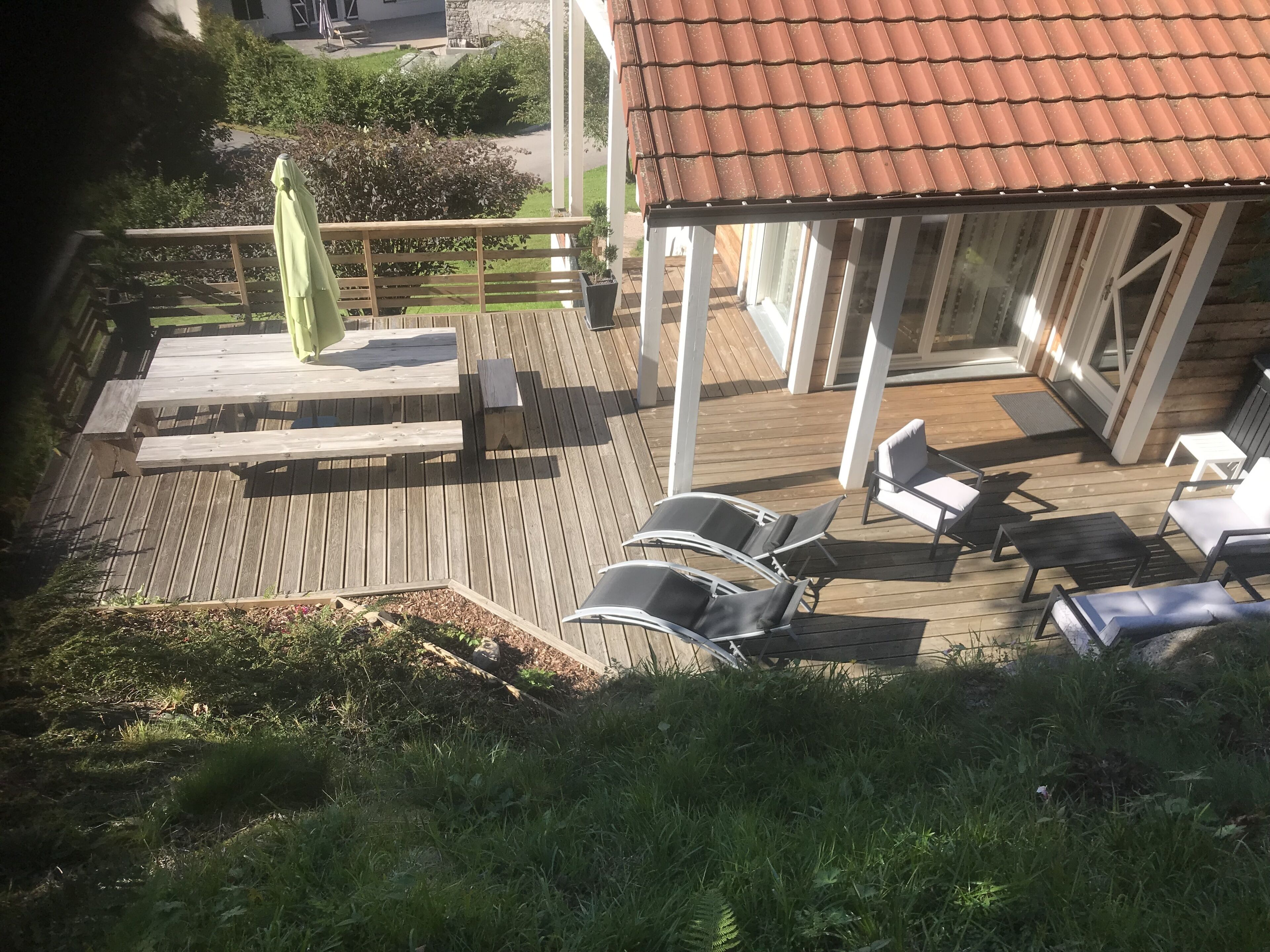 Una terraza de madera con sillones de descanso y un porche cubierto.