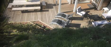 Una terraza de madera con sillones de descanso y un porche cubierto.