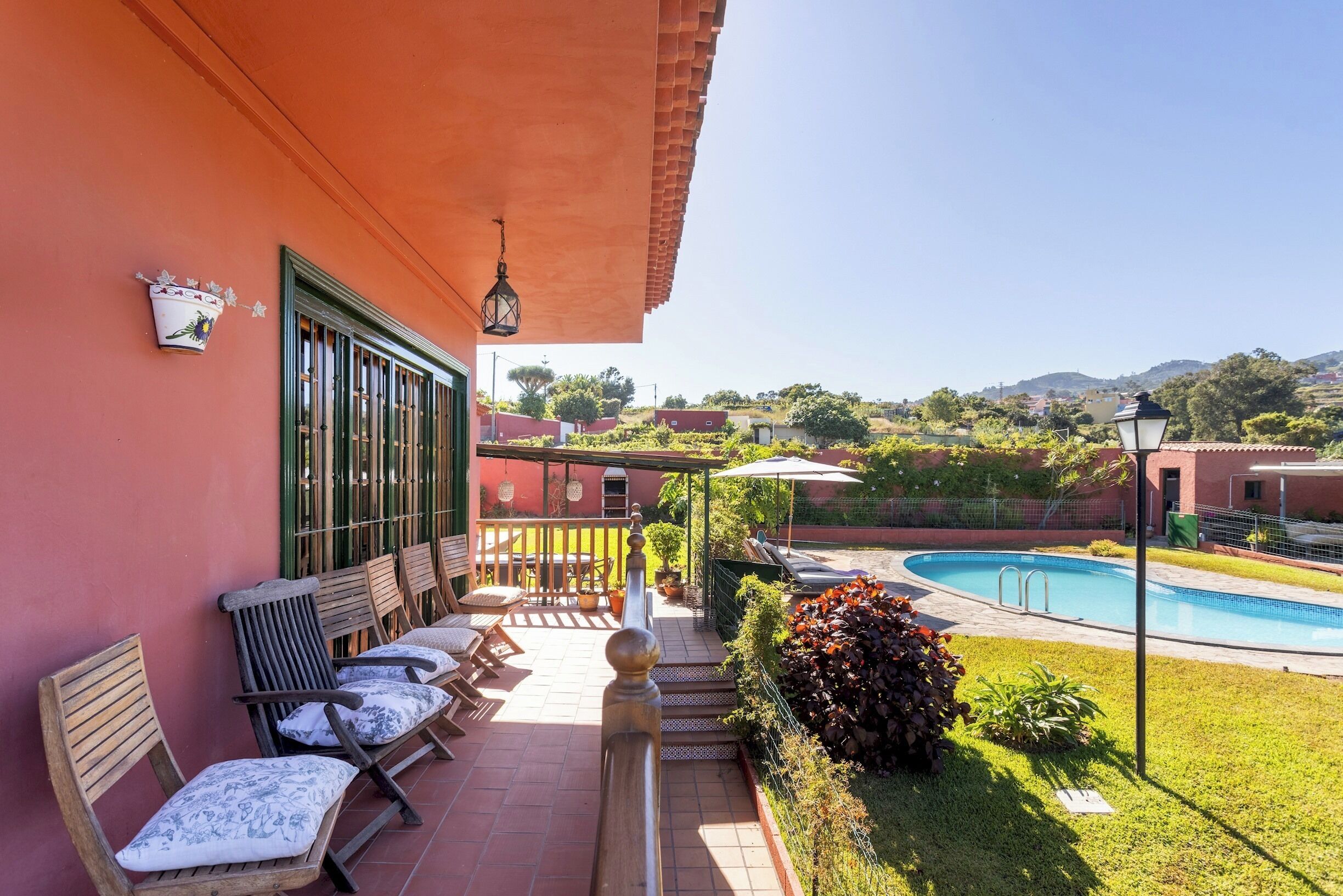 A balcony with a pool, chairs, and a view of the surrounding landscape.