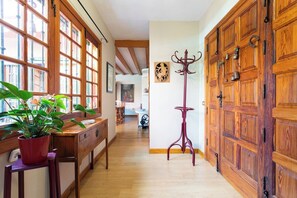 A hallway with wooden flooring, a bench, a potted plant, and a coat stand.