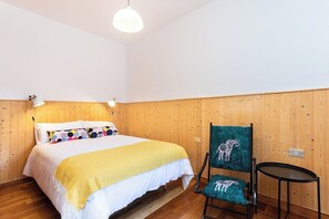 Un dormitorio con una cama, una silla y una mesita.