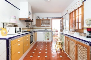 A kitchen with a tiled floor, wooden cabinets, a microwave, and a sink. - Home2Book Luxury Villa Luna de Tacoronte Pool (San Cristóbal de La Laguna)