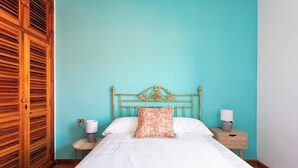 Une chambre à coucher avec un lit, une table de chevet, une lampe et une armoire en bois.