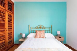 A bedroom with a bed, a nightstand, a lamp, and a wooden wardrobe. - Home2Book Luxury Villa Luna de Tacoronte Pool (San Cristóbal de La Laguna)
