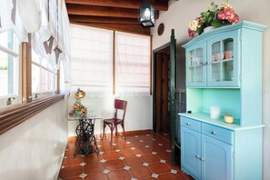 Una habitación con piso de baldosas, un armario azul con puertas de cristal, una máquina de coser y una silla.