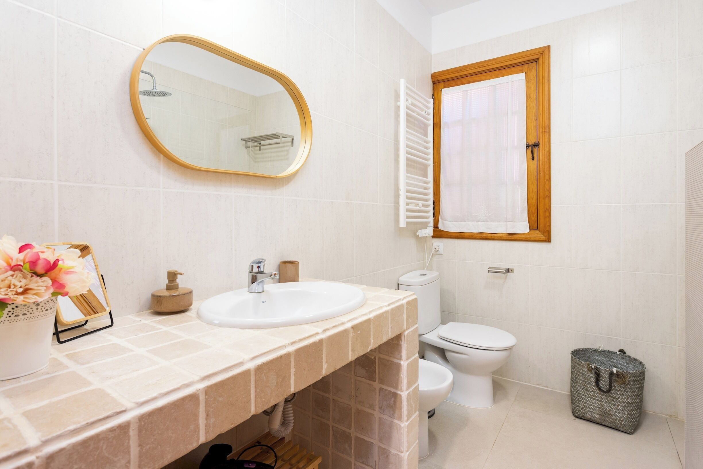 A bathroom with a white sink, a mirror, a toilet, and a shower.