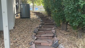 A stone pathway leading to a building entrance, surrounded by gravel and rocks. - Spread out in a large,1600 sq foot comfort suite 1 bedroom plus additional nook (Longmont)