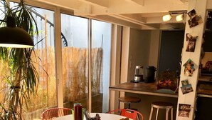 A modern kitchen with a dining area, large windows, and a potted plant. - Maisonette with terrace 5 minutes from the beaches (Anglet)