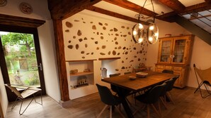 Ein Essbereich mit Holztisch und -stühlen, einer Steinsäule und einem Holzschrank mit Glastüren.