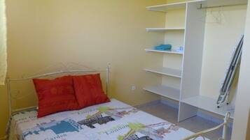 Cozy retreat with a single bed, cityscape-print quilt, and metal shelf unit.