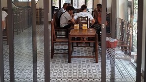 A dining area with a patterned floor, a table with chairs, and a view through a glass partition. - Tam coc Paradise Homestay (Nam Hoa Lu)