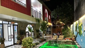 An outdoor pool area with a motorcycle parked nearby, surrounded by potted plants and a mural on the wall. - Tam coc Paradise Homestay (Nam Hoa Lu)