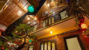 A multi-level building with a wooden interior, balconies, and hanging plants. - Tam coc Paradise Homestay (Nam Hoa Lu)