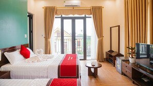A hotel room with two beds, a TV, a desk, and a balcony with curtains. - Tam coc Paradise Homestay (Nam Hoa Lu)