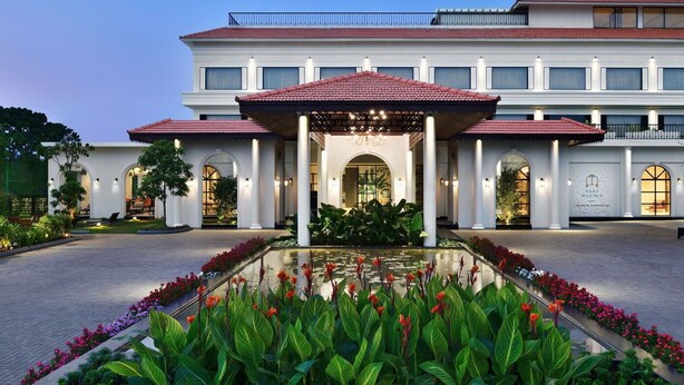 A two-story hotel with a central courtyard, a fountain, and a well-maintained garden. - Port Muziris, a Tribute Portfolio Hotel by Marriott, Kochi Airport (Aluva)