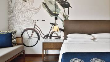 Een slaapkamer met een bed, een houten nachtkastje, een fiets en een muurschildering.