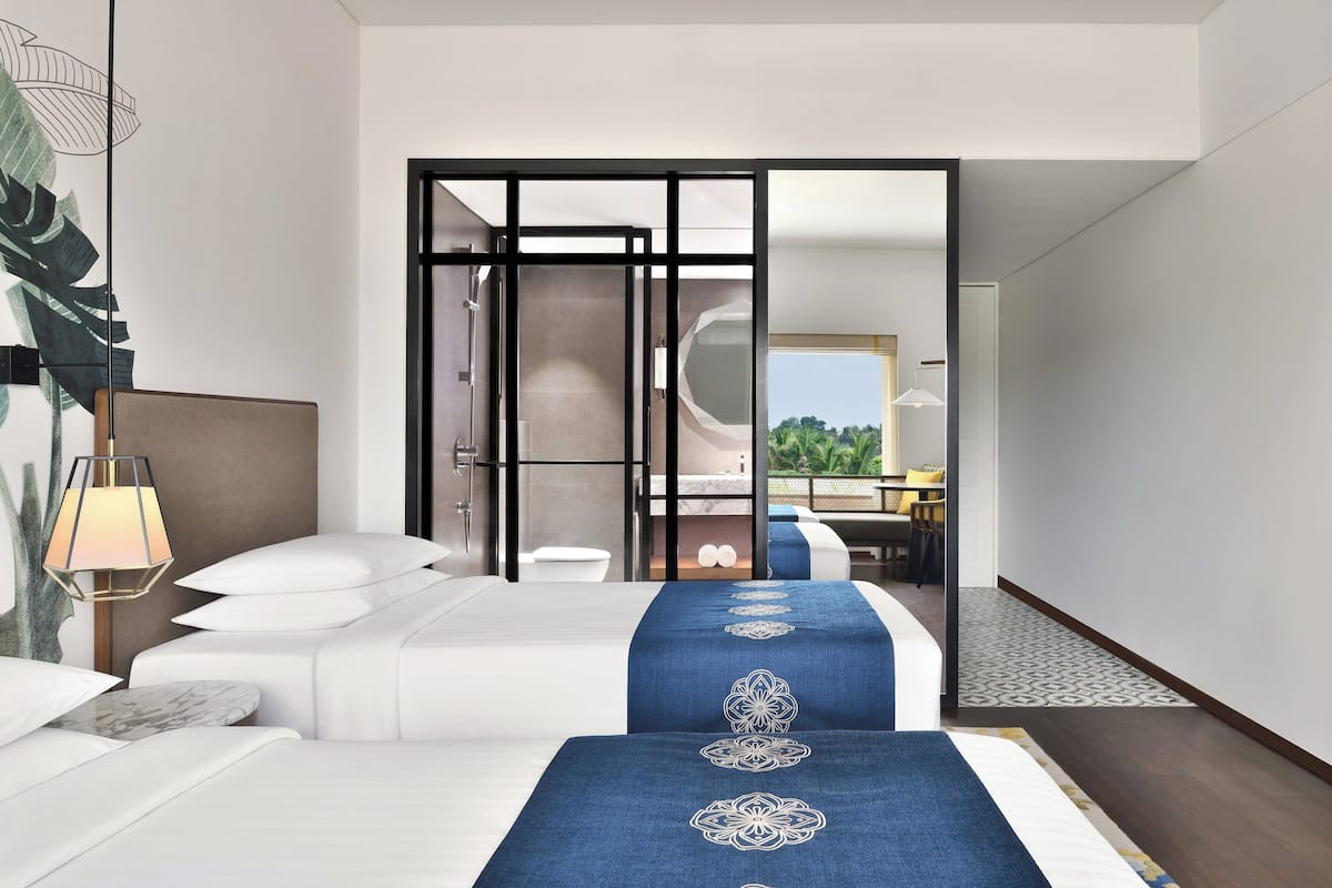 A modern hotel room with a bed, a desk, and a view of the outdoors.