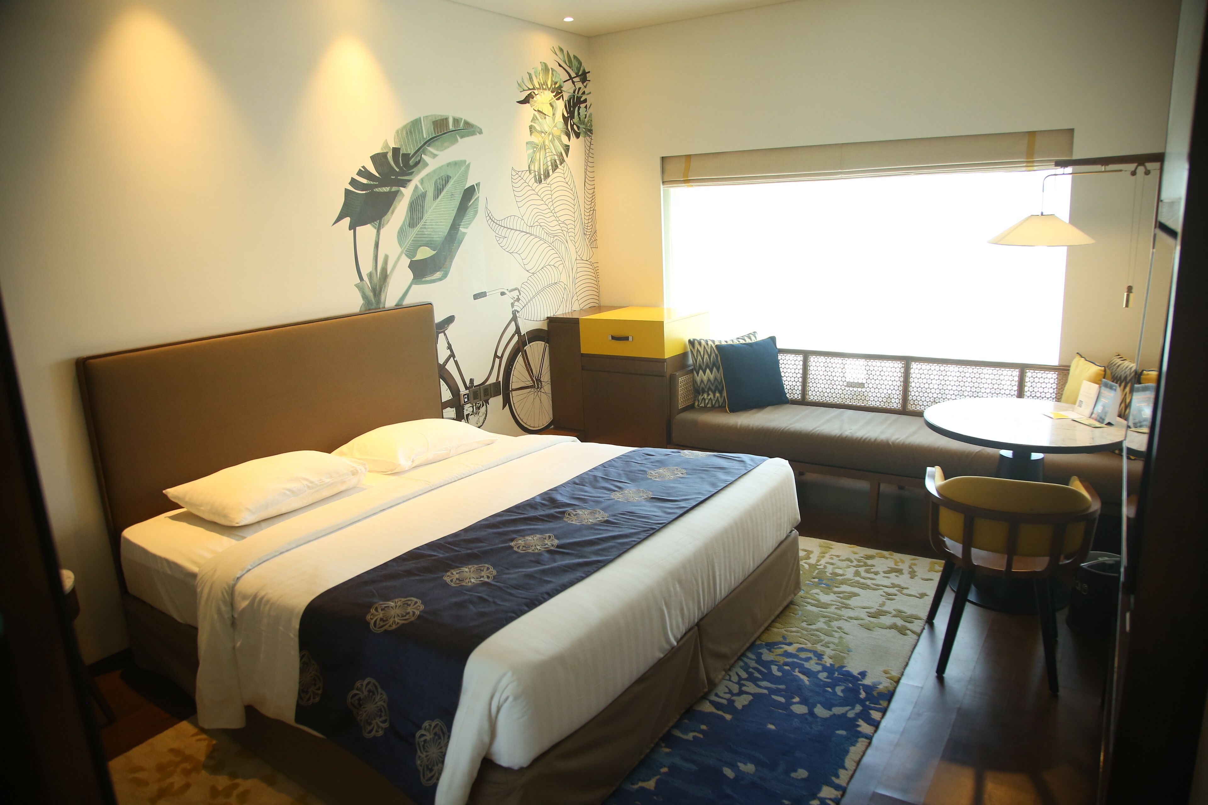 Habitación de hotel con cama, una mesita, una silla y ventana con vistas.