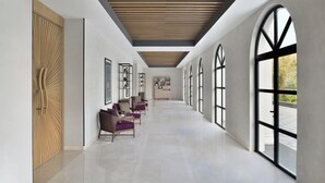 A modern interior with a long hallway, large arched windows, and a wooden ceiling. - Port Muziris, a Tribute Portfolio Hotel by Marriott, Kochi Airport (Aluva)
