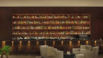 A bar area with multiple shelves of liquor bottles, a bar counter, and seating with a fire feature.