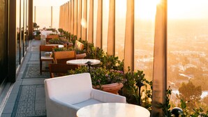 Une terrasse avec des places assises extérieures, une vue sur la ville et un coucher de soleil.