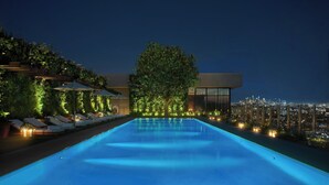 A rooftop infinity pool with lounge chairs and a cityscape view at night. - The West Hollywood EDITION (West Hollywood)
