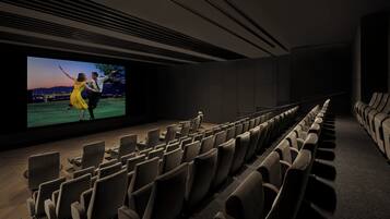 An empty movie theater with rows of seats and a large screen displaying a film.