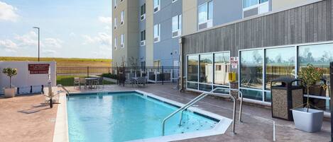 Een modern gebouw met een zwembad, terras en een bordje 'No Diving'.