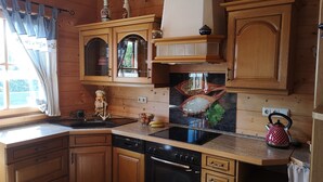 Une cuisine avec des meubles de rangement en bois, une cuisinière noire et une bouilloire rouge.