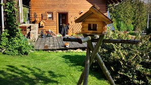 Une cabane en bois avec un toit en pente, un porche à l’avant et une petite structure en bois qui ressemble à une nichoir.