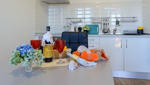 A kitchen with white cabinets, a stainless steel range hood, and a window with blinds. - Recanto das Florenças (2) – Great Views & Sunsets (Arco Da Calheta)