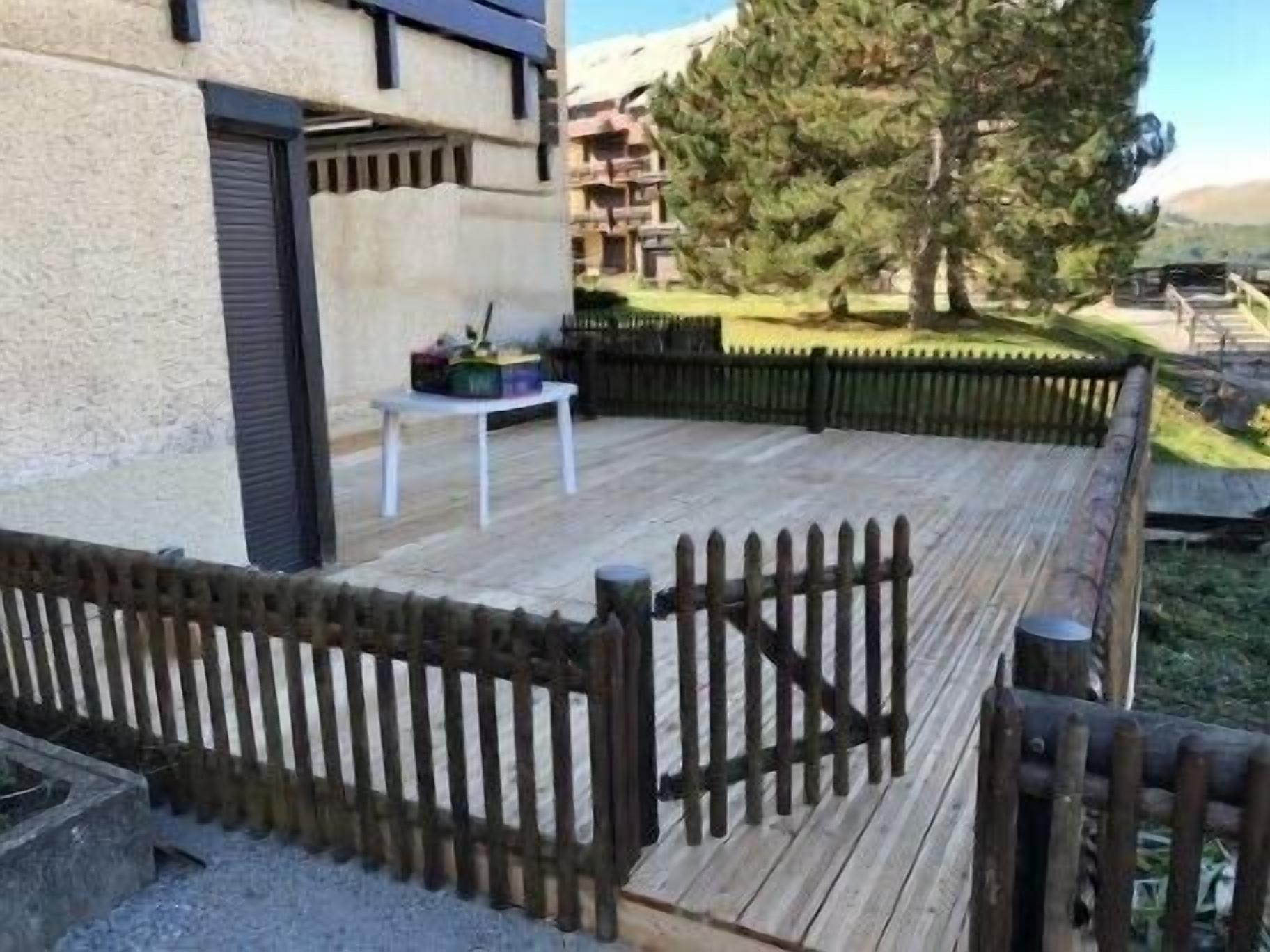 A wooden deck with a table and chairs, surrounded by a wooden fence.