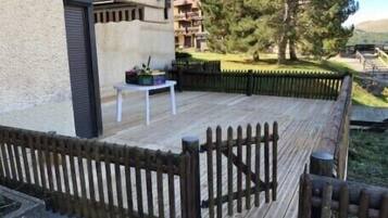 A wooden deck with a table and chairs, surrounded by a wooden fence.