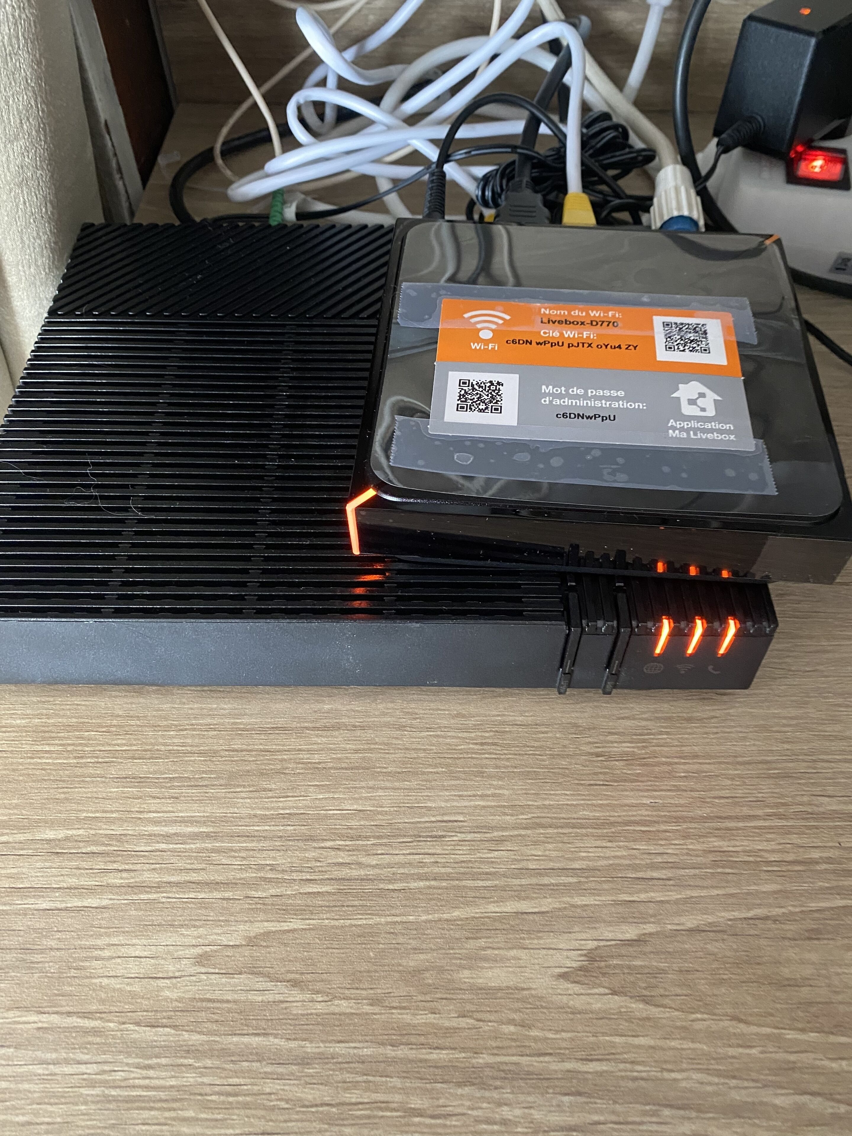 Un appareil muni d’une étiquette indiquant qu’il s’agit d’un routeur Wi-Fi, et qui est branché sur une multiprise dotée de plusieurs câbles.