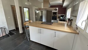 A modern kitchen with a central island, built-in oven, and stainless steel appliances.
