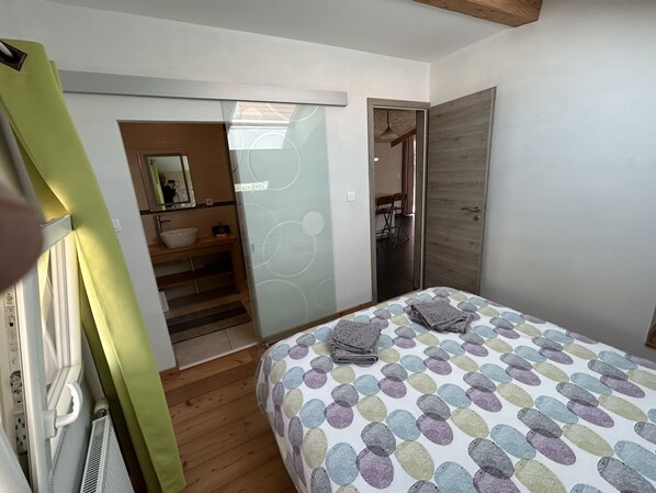 A bedroom with a bed, a bathroom with a sink, and a mirror.