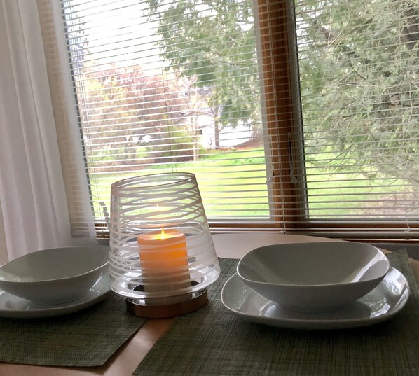A candle in a glass holder on a table with two bowls.