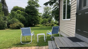 Eine Terrasse mit zwei Stühlen, einem kleinen Tisch, einer Laterne und einem Holzdeck.