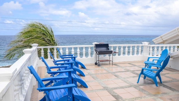 Un balcó amb caires blaus i una barbacoa, amb vista al mar.