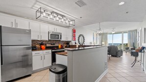 A modern kitchen with stainless steel appliances, a central island, and a dining area with a view.