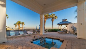A pool area with a hot tub, lounge chairs, and palm trees.