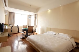A hotel room with a large bed, a desk with a computer, a chair, and a television.