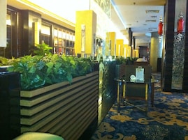 A lobby with a reception desk, a plant wall, and a patterned carpet.