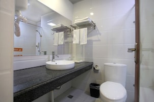 A modern bathroom with a granite countertop, white sink, and a toilet.