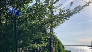 Un panneau de rue indiquant « Cherry St. », une clôture en bois peinte en blanc et, au loin, une étendue d’eau.