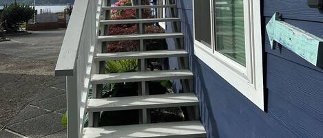 Une maison bleue avec un escalier blanc menant à une terrasse.