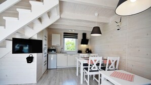 Una cocina moderna con armarios blancos, una zona de comedor con sillas blancas y una escalera con barandillas blancas.