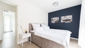 Een slaapkamer met een bed, nachtkastje en twee aan de muur hangende foto’s.